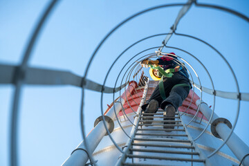 Industrial technician carefully climbing down a ladder on a storage tank, demonstrating controlled descent and compliance with workplace safety standards.