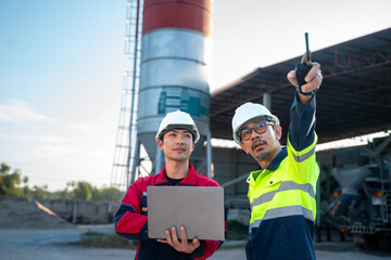 Senior engineer pointing toward equipment while colleague holds a laptop, illustrating leadership, communication, and coordinated decision making at an industrial facility.
