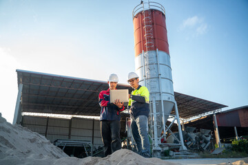 Wide shot of engineers working together in front of a tall industrial silo, combining digital tools with traditional industrial inspection.
