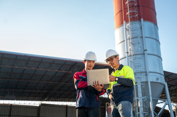 Engineers walking on industrial site while reviewing laptop data, showing active supervision and mobile project management.