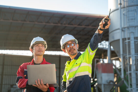 Engineers discussing next steps at factory site with laptop and hand gestures, representing strategic planning and collaborative engineering work.