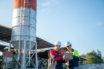 Engineers working together with laptop and handheld device at industrial site, demonstrating communication, supervision, and real-time coordination.