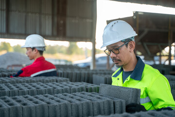 A factory staff member performing a physical check on a single block, verifying its weight and solidity before final approval.