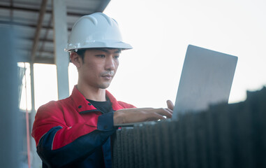 An engineer inputting real-time data into a laptop positioned on a stack of construction materials at the job site.
