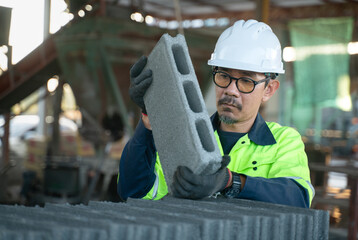 A technician lifting a hollow concrete block to eye level to rigorously inspect its structural integrity and finish.