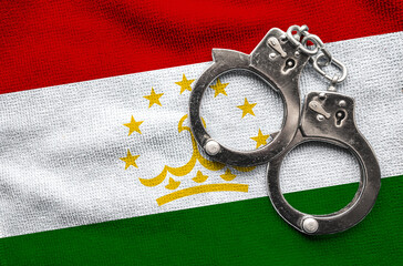 Flag of Tajikistan and police handcuffs. Crime and offenses in country Concept
