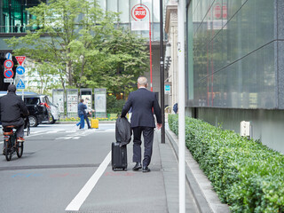 朝の通勤時間の東京都の街で歩く通勤中の中年男性サラリーマンの姿