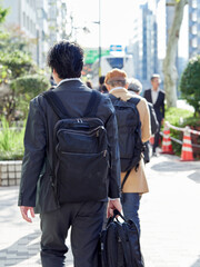 朝の通勤時間の東京都の街で歩く通勤中の中年男性サラリーマンの姿
