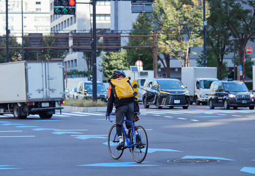 東京都の街の交差点を渡る自転車を乗る若者の姿