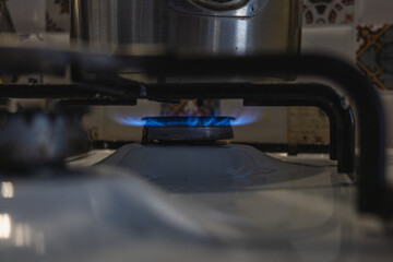 Gas flame burning on a stove with pot in kitchen setting