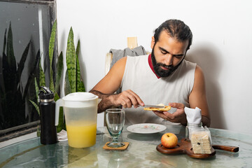 Person spreading topping on toast at glass table with juice and breakfast items