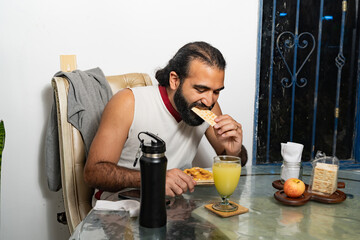 Person eating cracker at breakfast table with juice, apple, and snack items