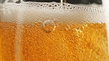 A refreshing closeup shot of golden beer being expertly poured into a clear glass creating a rich frothy head and countless effervescent bubbles rising from the bottom highlighting the crisp and invi.