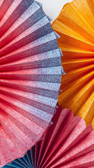 Abstract close up of layered colorful paper fans creating geometric patterns and vibrant textures.