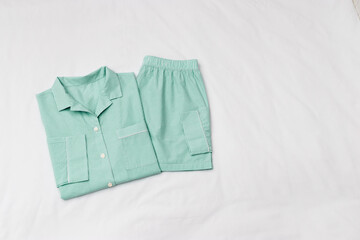 Green striped Pajama Set on white sheet background. Top view home sleepwear female from soft cotton trend mint green colored on bedclothes. Cozy pyjamas of shirt and shorts for comfort rest, flatly