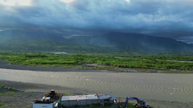 A pull-out ground aerial at the Chico River reveals shaded mountains in the distance and sunbeams peeking left Bontoc, Nueva Vizcaya, Philippines