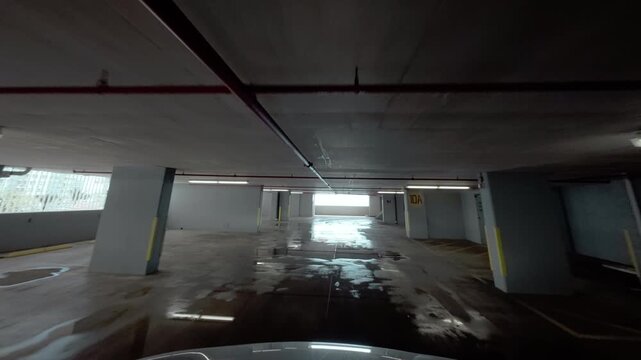 The multilevel parking garage lot at the modern building. Car moves inside the building along parked cars.