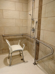 Medical shower chair with grab bar for senior and disability person in bathroom care home facility.