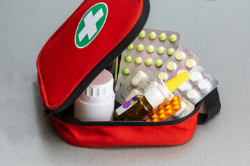 Open first aid kit with pills, bottles of medicine on the table , close-up.