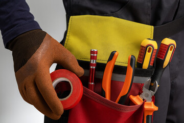 Electrician at work, hand in glove holding red insulation tape. electrician services.