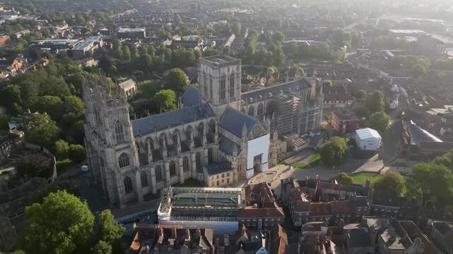 Aerial drone point of interest shot rotating clockwise around the main entrance of York Minster, gradually revealing the sunrise and early morning light over the Gothic cathedral in York, England.