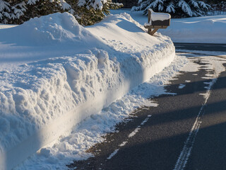 Obraz premium Snow-covered road with mailbox and snowbank during winter 