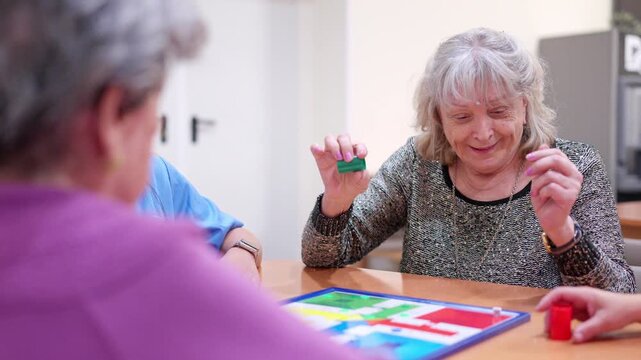 Elderly caucasian woman playing Parcheesi board game