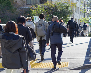 朝の通勤時間の東京都内のオフィス街で歩く大勢な通勤中の男女会社員の姿