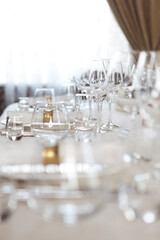 Festive table setting. Wine glasses and plates on the table. A white tablecloth. A cotton serving napkin with a yellow metal ring. The concept of the holiday.