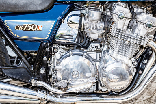 Close-up of a classic Honda CB750C motorcycle engine with polished chrome parts and blue side panel, highlighting vintage Japanese engineering and mechanical detail.