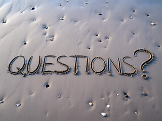 Questions written in the sand on a beach as a symbol of inquiry