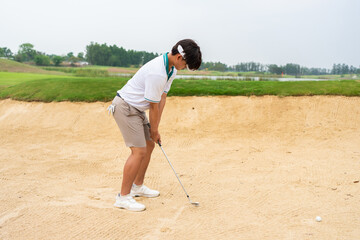 Professional young male golfer swings his club on scenic golf course. 