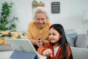 Asian loving grandmother support granddaughter with homework at home. 