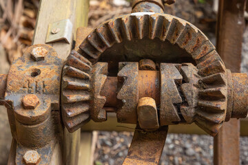 A rusted gear and cog system with bevel teeth designed to change the direction of the drive power on an old, retired farm machine on the Gold Coast in Queensland, Australia. 