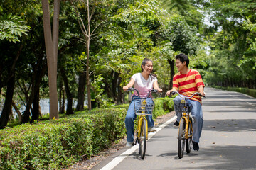 Obraz premium Asian young couple dating and biking together on a road in the park. 