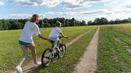 Mom teaches boy to ride a bike