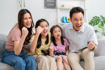 Fototapeta premium Asian happy family enjoying games with their little girl daughter. 