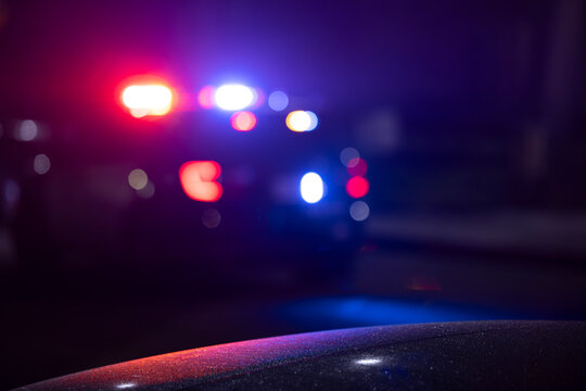 Abstracted illuminated night view of police units on a city street.