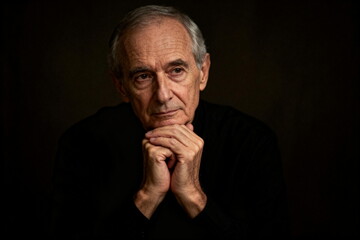 Portrait of a thoughtful senior man with hands clasped