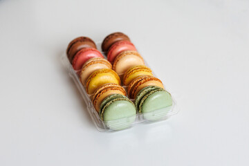 Colorful macarons assortment in plastic tray on white background
