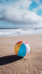 Vibrant beach ball rests on sand bathed in summer sunshine a peaceful coastal scene unfolds