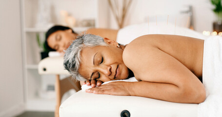 Women, sleeping or acupuncture therapy with massage bed for spa, body treatment or healing in salon. Mature, female people or relax on holiday getaway together with comfort for zen or beauty session
