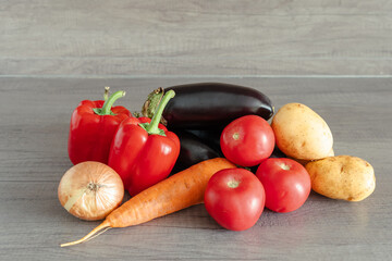 A vegetable harvest on a wooden table. Carrots, eggplant, bell peppers, and tomatoes are healthy and nutritious