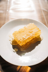 Golden honeycomb dripping honey on white plate