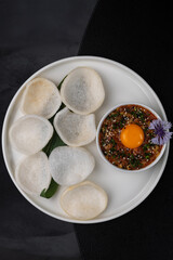 Tartare with egg yolk and rice chips on a white plate isolated