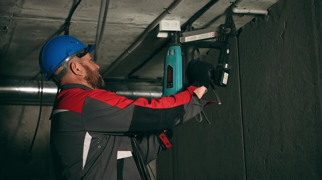 Meticulous Technician Carefully Fastening Ceiling Wiring And Junction Box Amidst Industrial Surroundings