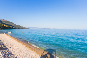 Tranquil pebble beach meets crystal-clear turquoise waters under a bright blue sky