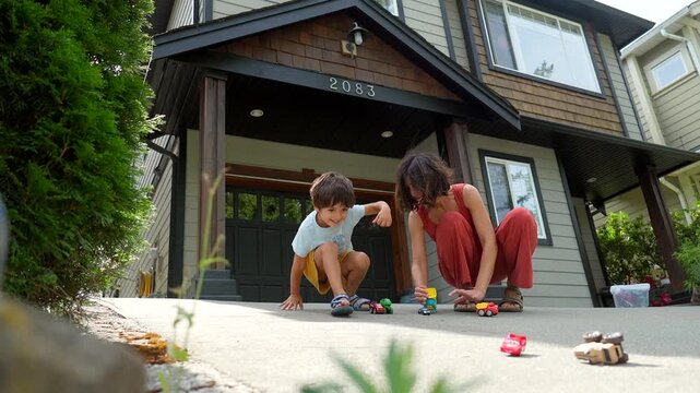 Happy family moments unfold as a mother engages in playtime with her son, sharing laughter and creating cherished memories together in the driveway of their home