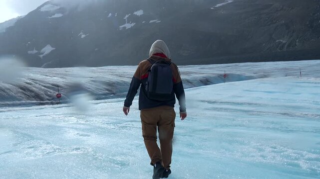 Backpacker walking on athabasca glacier in jasper national park, a popular tourist destination and part of the columbia icefield in the canadian rockies