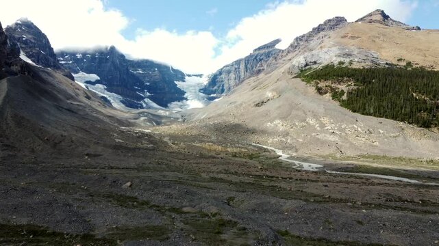 Sunlight illuminates the rugged terrain of the columbia icefield in jasper national park, canada, casting shifting shadows as the sun moves across the sky